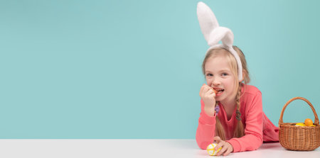 Easter child. Funny girl wearing bunny ears and having fun with Easter eggs. Cute little child girl wearing bunny ears on Easter day. Panoramic web banner frame.の写真素材