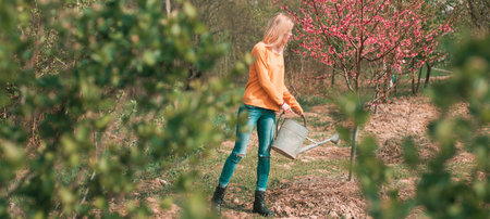 Spring woman. Happy young woman gardener spraying water on plants. Hobby concept. Girl gardening on...