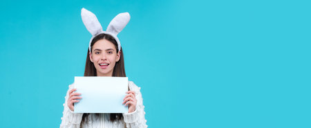 Happy Easter. Portrait of Easter bunny girl hold paper for text. Model dressed in costume Easter bunny rabbit. Wide photo banner for website header design.の写真素材