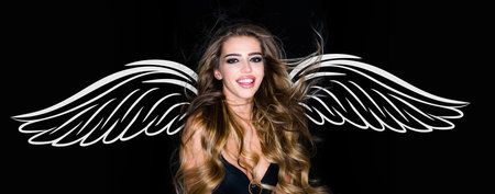 Angel woman with wings. Valentines day banner for website header design. Studio fashion shot. Beautiful cheerful and enjoying woman. Blonde woman with curly beautiful hair smiling on black background.の写真素材