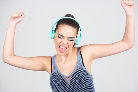Dj girl. Image of amazed woman listening to music with headphones isolated over studio background. Excited young girl with headphones listening to music and dancing. Sexy woman enjoying songs.の写真素材