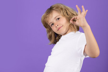 Portrait of cute smiling child with okay gesture, isolated studio background. Successful kid gesturing, excellent sign, ok gesture.の写真素材