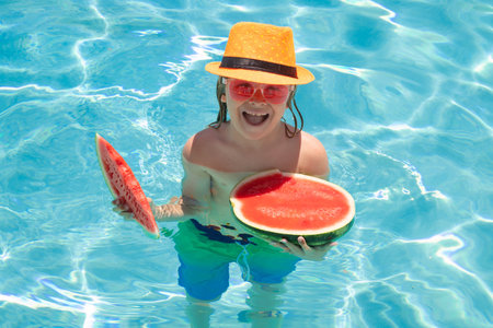 Child eat watermelon in the pool. Summer kids face.の写真素材