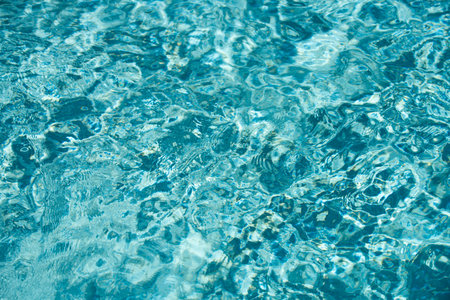 Water background. Blue water, ripples and highlights. Texture of water surface and tiled bottom.