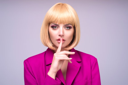Shh shy sly woman. Close up portrait of cute lovely girl making hush gesture isolated on studio background. Young woman asking to be quiet with finger on lips. Silence and secret concept.の写真素材