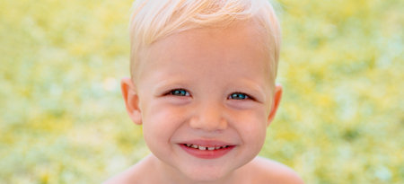 Banner with spring kids portrait. Closeup face of cute smiling spring child. Kid emotions concept. Portrait of young laughing boy outdoor.の写真素材