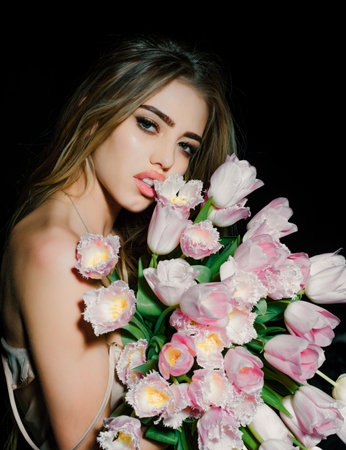 Sexy sensual young woman with tulips flowers bouquet. Spring woman on black.