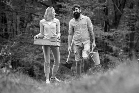 Couple of farmers walking in agricultural field. Gardening in spring - happy couple harvesting and...