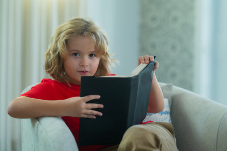 Kid boy reading book at living room. Concept of education, childhood, book reading and inspiration.