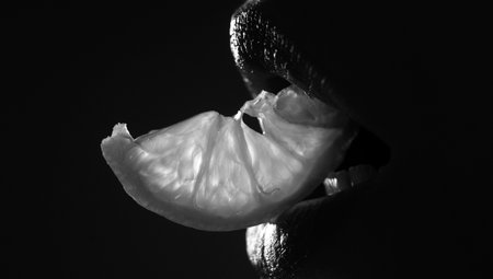 Closeup lips with lemons. Sexy fruit. Vitamin C. Summer refreshment. Girl with slice of lemon. Macro of mouth chewing yellow citrus.の写真素材