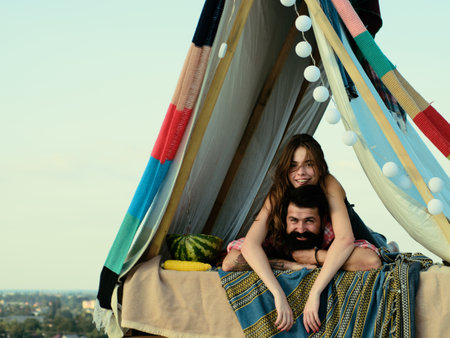 Couple camping and hug on nature. Romantic lovers in tent at countryside. Couples lovers camping in forest in summer time.の写真素材