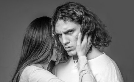 Attractive young couple hugging each other on grey background. Young man and woman in cuddle. Young...