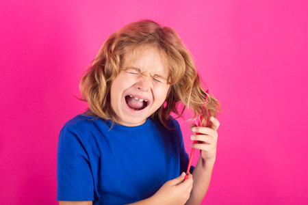 Conditioner and shampoo for kids hair. Little kid combing hair, isolated studio background.の写真素材