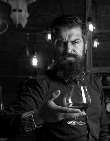 Drinking man. Retro bar. Handsome pensive man is holding a glass of whiskey or cognac.