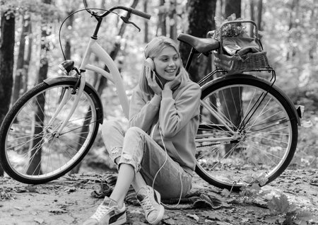 Musical pause. Enjoy relax forest. Girl ride bicycle for fun. Warm autumn. Girl with bicycle and headphones. Woman with bicycle autumn forest. Weekend activity. Active leisure and lifestyleの写真素材