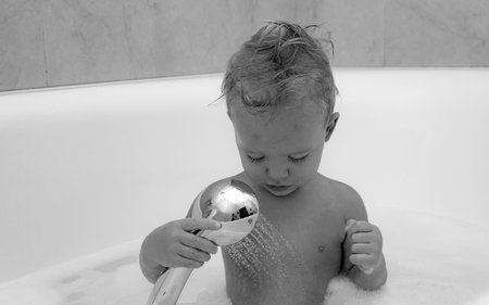 Happy baby having a bath and playing with toys. Lovely child playing with foam. Smiling and laughing...