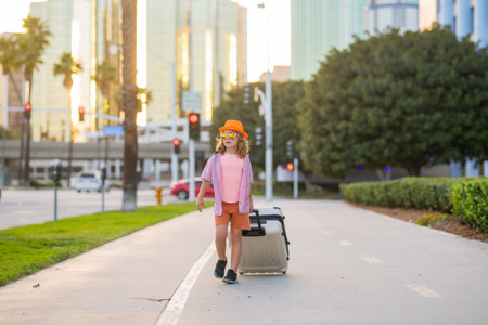 Child boy going on summer trip, holding luggage travel bag outdoor. Kids travel and journey weekend trip.の写真素材