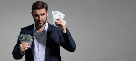Portrait business man holding cash dollar bills over gray background. Big luck, banner. Dollar cash money concept. Rejoices to win cash. Man hold cash money. Financial luck and success.の写真素材