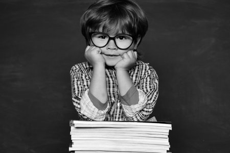 Cute boy with happy face expression near desk with school supplies. Happy school kids. School lessons. Hard exam. Educational processの写真素材