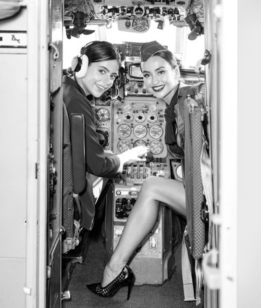 Women Pilot and Flight Instructor in Aircraft Cockpit. Beautiful Smiling Young Women Pilots Sitting in Cabin of Aircraft. Portrait of attractive young woman pilot with headset.の写真素材