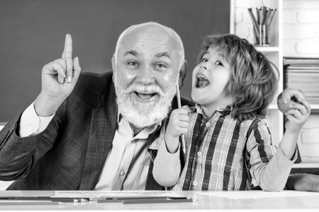 Pupil and Teacher in classroom. Grandfather and son having fun together. Mature man teacher and...