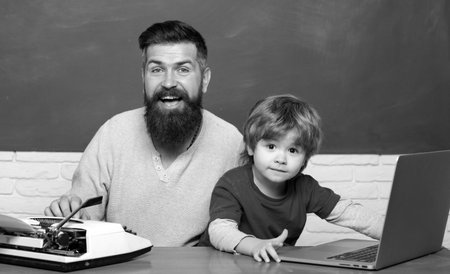 Teacher helping kids with their homework in classroom at school. Back to school. Parent Teacher. Man teaches child. First day in school. Young adult concept. Father and son.の写真素材
