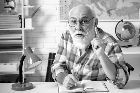 World teachers day. Grandfather teacher. Portrait of funny mature teacher in classroom Portrait of happy senior teacher sitting in classroom.の写真素材