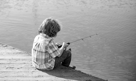 Child fishing. Young fisher. Boy with spinner at river. Portrait of excited boy fishing. Boy at jetty with rod. Fishing concept.の写真素材