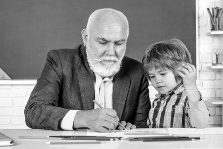 Happy Son and Grandfather sitting at a desk indoors. World teachers day. Family generation and relations concept.の写真素材