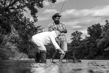 Fisherman in formal suit. Portrait two men on holiday. Men relaxing nature background. Catching and...