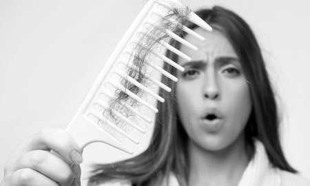 Hair loss woman with a comb and problem hair. Hairloss stressed woman and bald problems.の写真素材