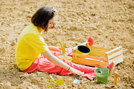 Kid portrait on farmland. I like spending time on farm. Child girl having fun with little shovel and plant in pot.の写真素材