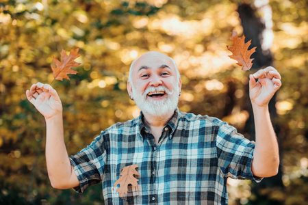 Elderly man smiling outdoors in nature. Grandfather relaxing in autumn park. Freedom retirement concept. Senior man walking in the park in autumn.の写真素材