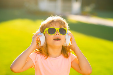 Singing children. Child with listening to music using headphones amazed with open mouth. Funny kids face.の写真素材