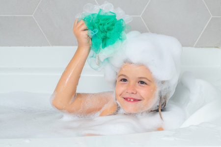 Boy child in a bath with foam. Kids bathing and hygiene procedures.