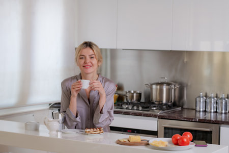 Blond beautiful girl drink morning coffee in kitchen at hame. Morning of pretty woman.の写真素材
