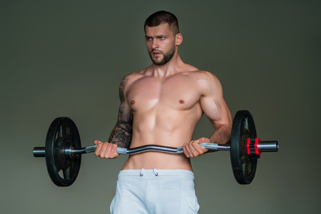 Muscular hunk with posing in gym. Fitness male model near gym equipment. Young muscular man workout. Sport man with strong muscular torso in gym. Sport and motivation. Exercises with weight.の写真素材