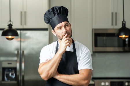 Portrait of chef man in a chef cap in the kitchen. Man wearing apron and chefs uniform and chefs hat. Character kitchener, chef for advertising.の写真素材