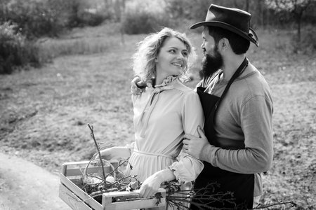 Portrait of a young happy couple in yard during spring season. Couple Farmers. Couple of farmers seedling sprouts in the garden. Family of rural workers.の写真素材