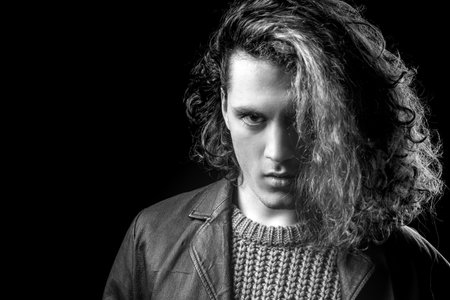 Man with serious face and brutal style. Young man tense face on black background. Perfect seductive confident man. Looking at camera.の写真素材