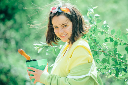 Kid planting flowers in pot. daughter planting flowers in ground. Little helper in garden Planting flowers. Child Farmer planting in the vegetable garden.の写真素材