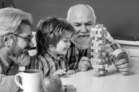 Grandfather Father and son playing indoors. Grandfather father and pupil son smiling against home...