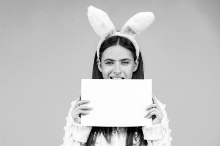 Portrait of funny Easter bunny woman hold board.の写真素材