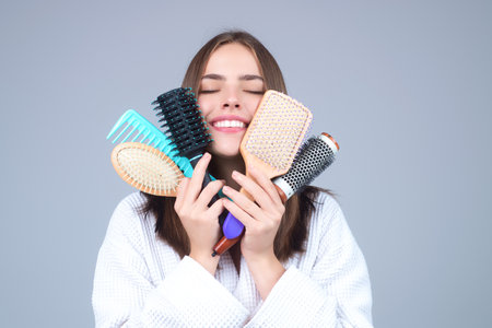 Beautiful model girl with comb brushing hair. Beauty woman with straight hair on studio background. Woman holding hairbrush near face. Healthy hair. Hairstyle and hair care concept. Shiny hairs.の写真素材