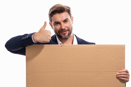 Handsome businessman in suit holding empty board on studio background. Business man with thumb up showing blank signboard with copyspace. Idea and offer. Your advertisement.の写真素材