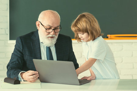 Teacher and child in classroom. Education concept. School learning concept. Boy elementary school. Old and Young.の写真素材