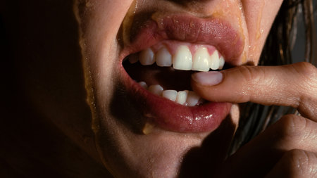 Sensual young woman face with honey drop close up. Sexy model with honey drip on face.の写真素材