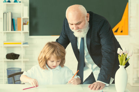 Schoolboy learning in classroom. School teacher help to learn. Education, teachering. Pupil kid lesson.の写真素材