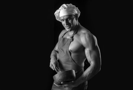 Sexy cooking chef in apron. Muscular man on black background. Sports diet.の写真素材