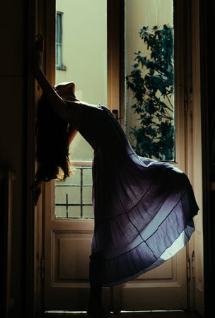 Seductive young woman in sensual nightie. Beautiful young woman with long dark hair. Outdoor on balcony with house view. Girl after morning coffee. Beauty and fashion.の写真素材